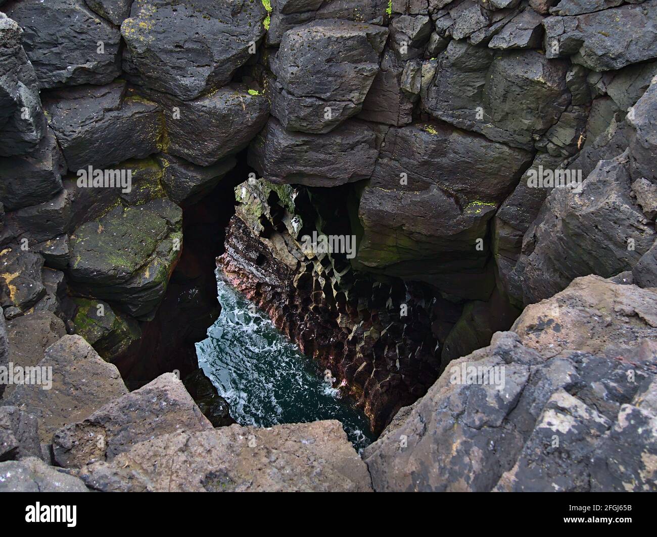Beautiful high angle view of a deep hole in the volcanic basalt rocks on the rough Atlantic coast of Snæfellsnes peninsula, west Iceland. Stock Photo