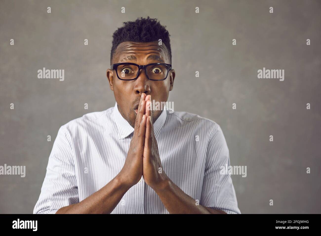 Studio portrait of shocked young African American man in glasses looking at camera Stock Photo