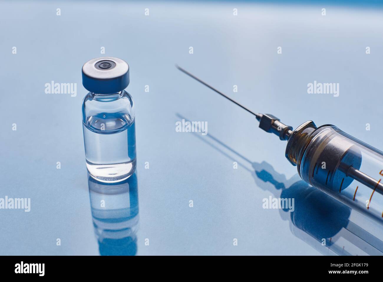 Glass vaccine vial and glass syringe on blue glass background Stock ...