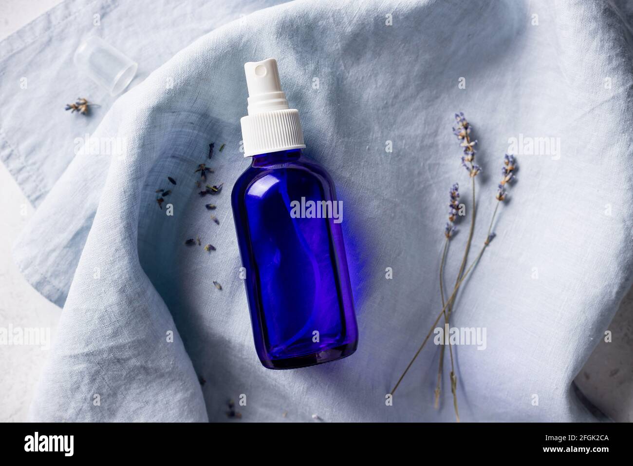 lavender spray in transparent glass bottle on linen sheet Stock Photo