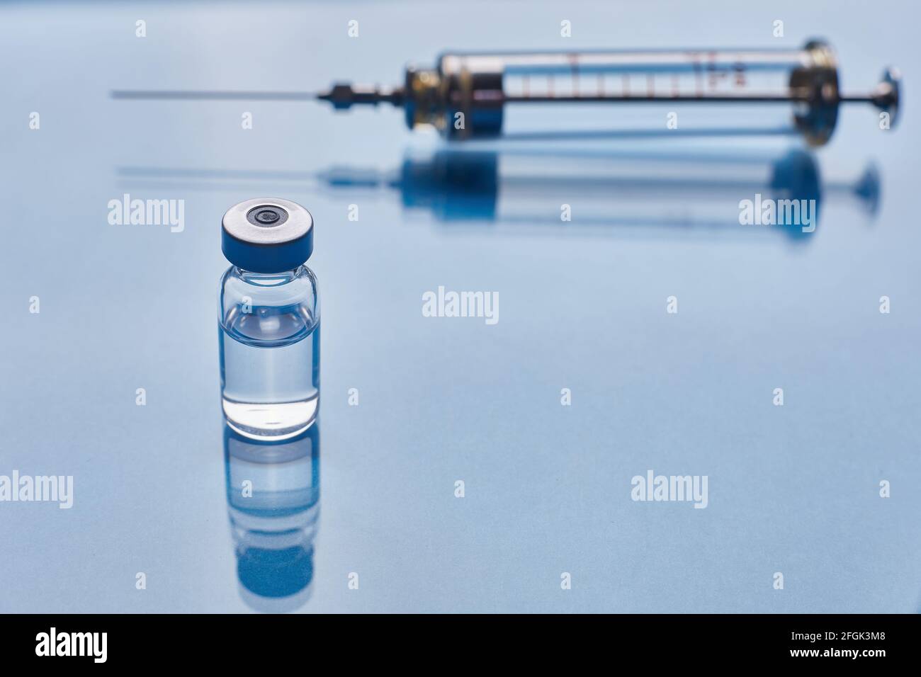Glass vaccine vial and glass syringe on blue glass background Stock ...