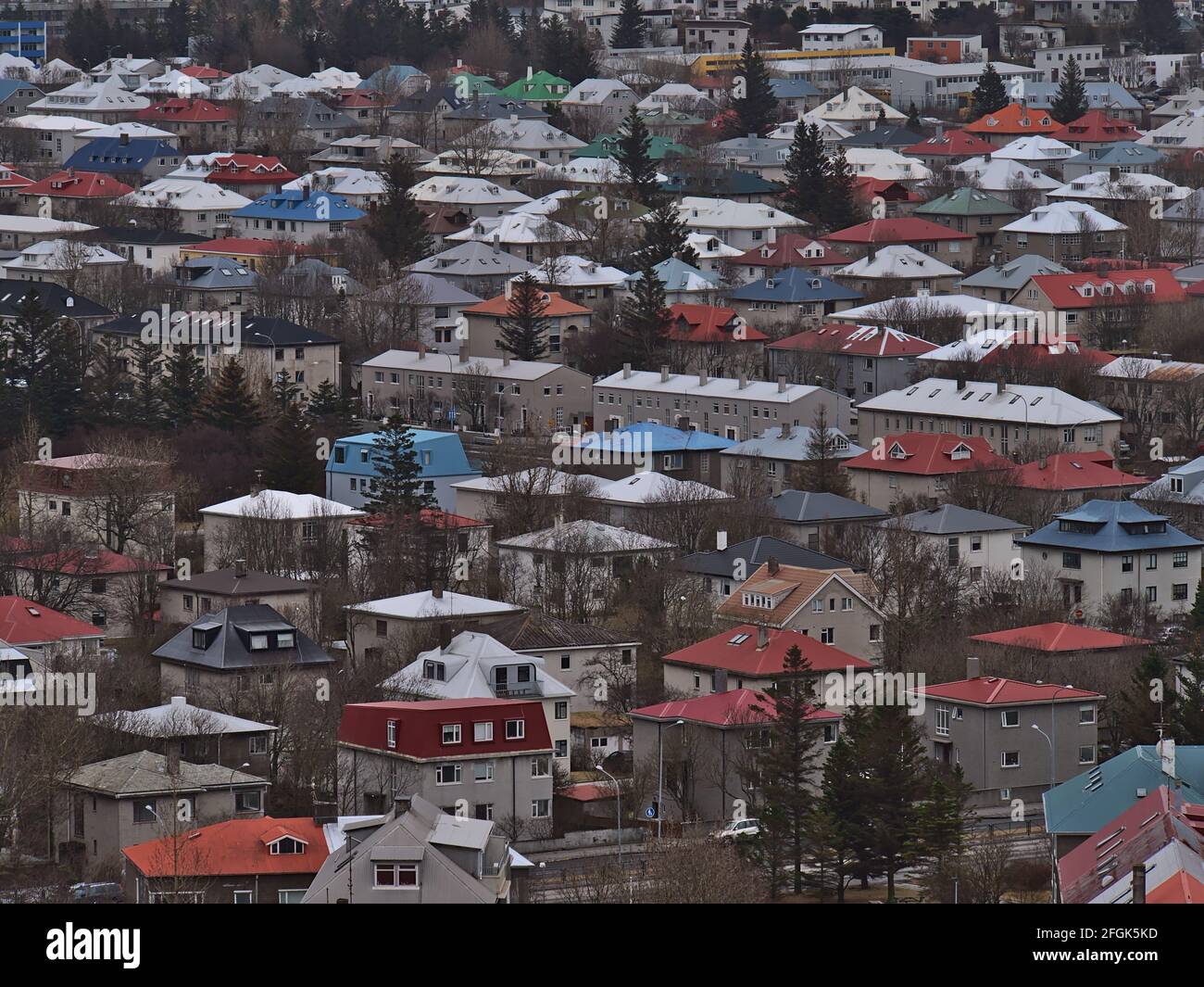 Beautiful aerial view of residential area in Reykjavík, capital of Iceland, with buildings, colorful rooftops and trees in between on cloudy day. Stock Photo