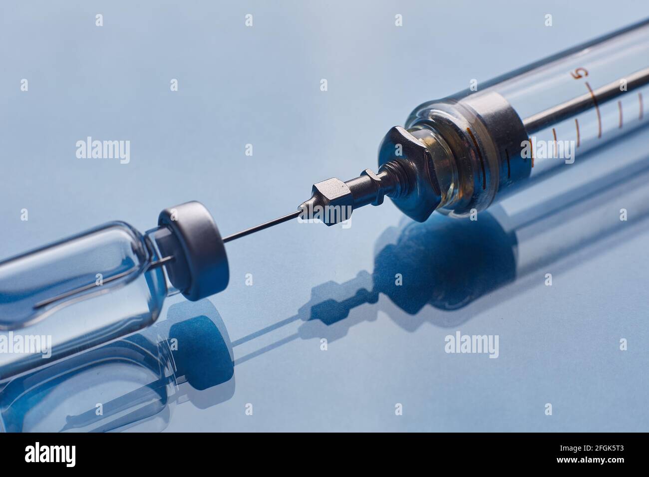 Glass vaccine vial and glass syringe on blue glass background Stock ...