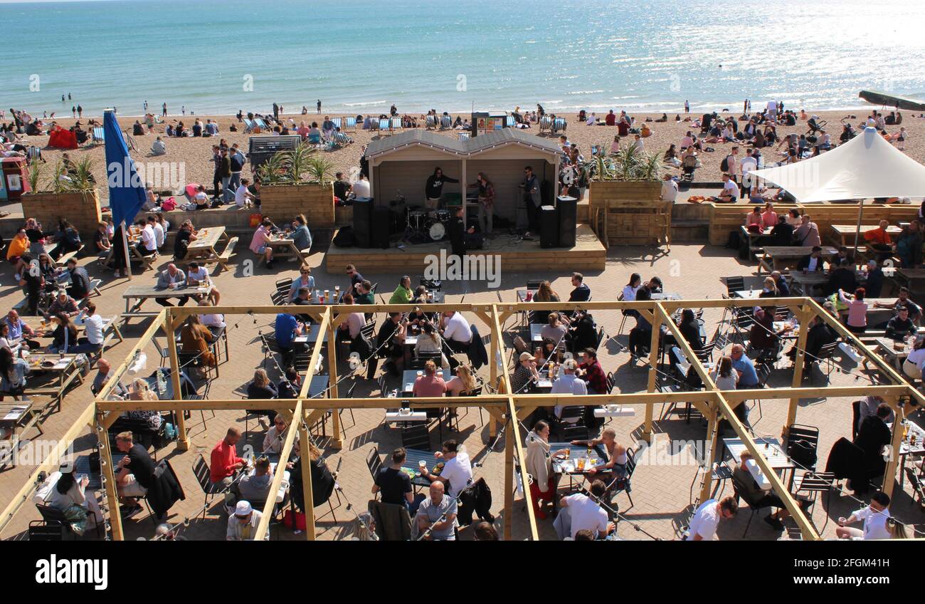 Crowds return to Brighton seafront pubs after lockdown restrictions are eased. Al fresco dining with people enjoying themselves. Lovely spring day. Stock Photo