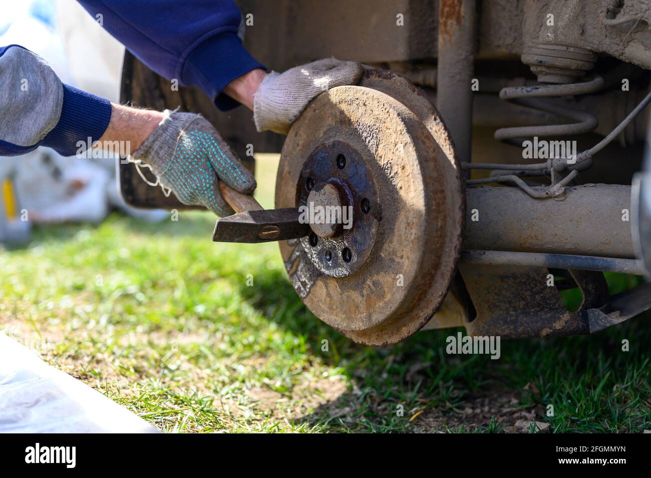men's gloved hands repair of car drum brake himself. disassembles a