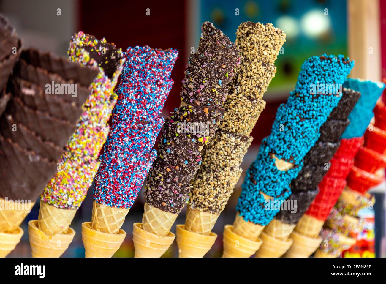 Chocolate dipped ice cream cones topped with sprinkles and chopped nuts Stock Photo