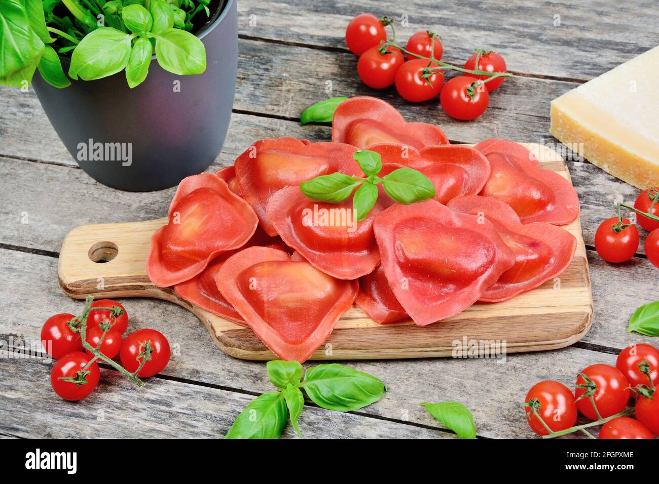 Red heart ravioli with tomato, mozzarella and basil on a wood background close up Stock Photo