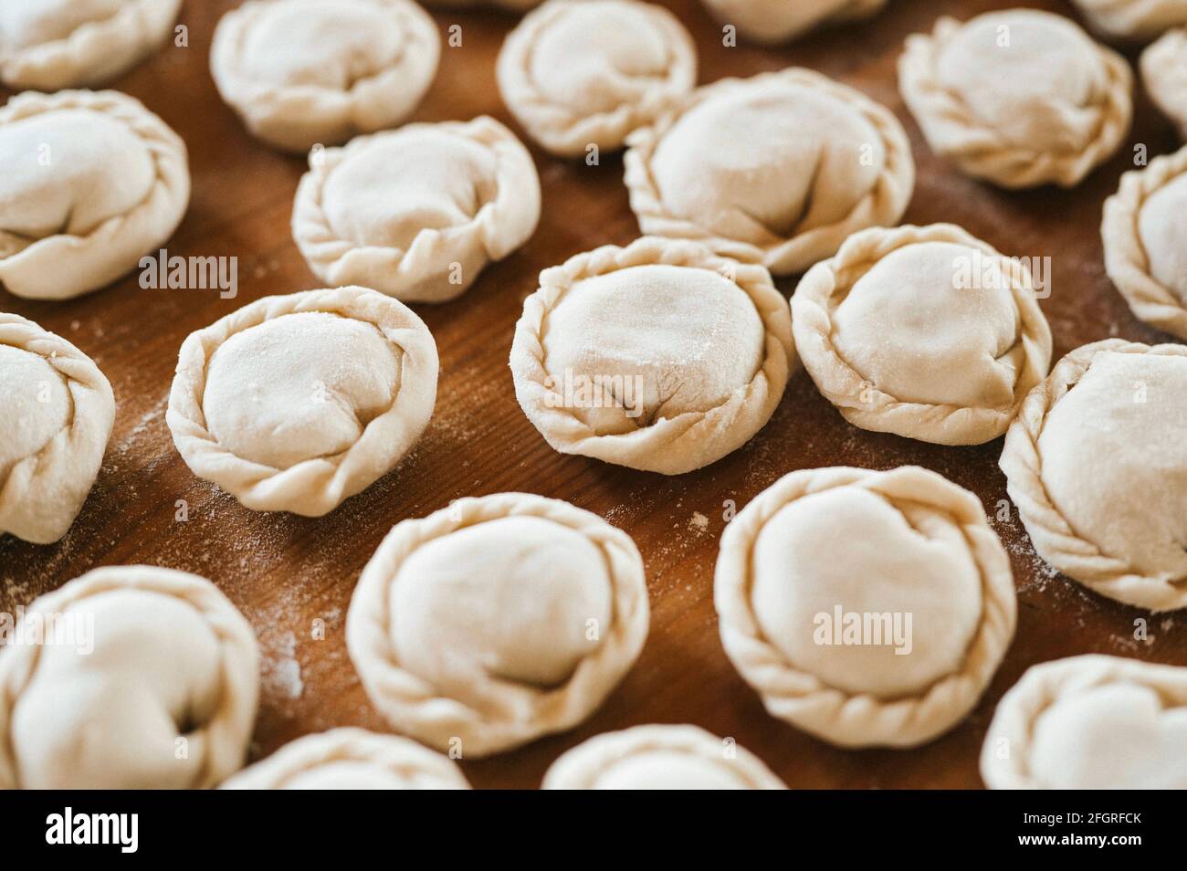 pile of small homemade uncooked dumplings with meat on kitchen 