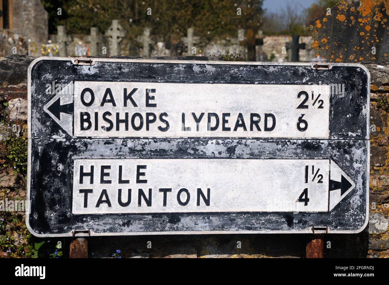 An old pre-Worboys directional road sign still in situ on the churchyard wall in Bradford-on-Tone, Somerset, England Stock Photo