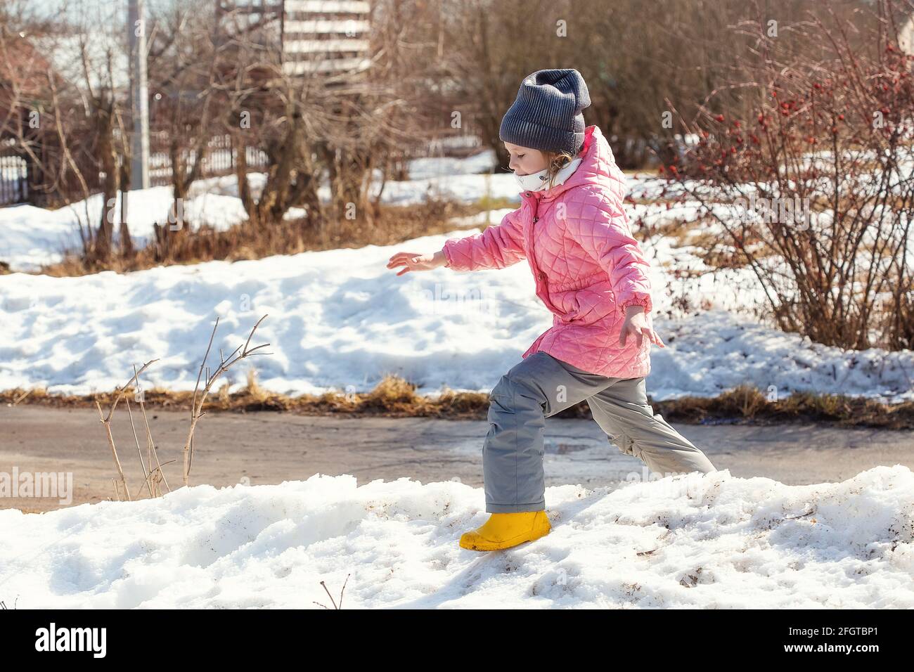 Little caucasian girl 5 years old in a pink coat plays in the snow on ...