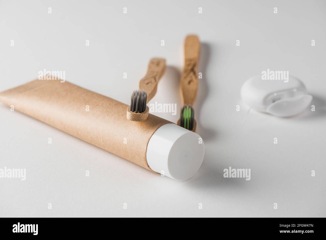 Close-up on a tube of toothpaste, bamboo toothbrushes and dental floss ...
