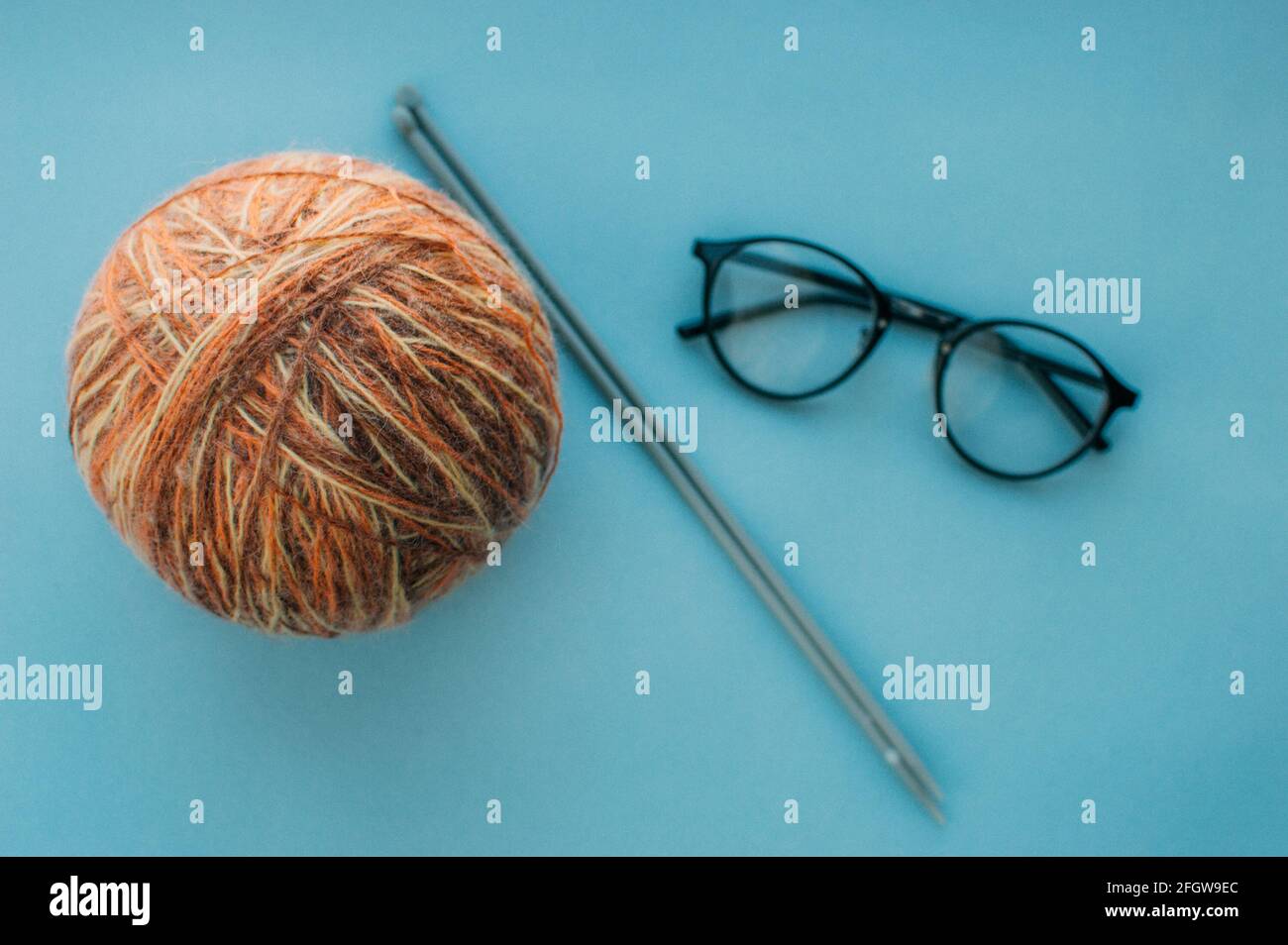 Ball of yarn, knitting needles and glasses. Flat lay Stock Photo