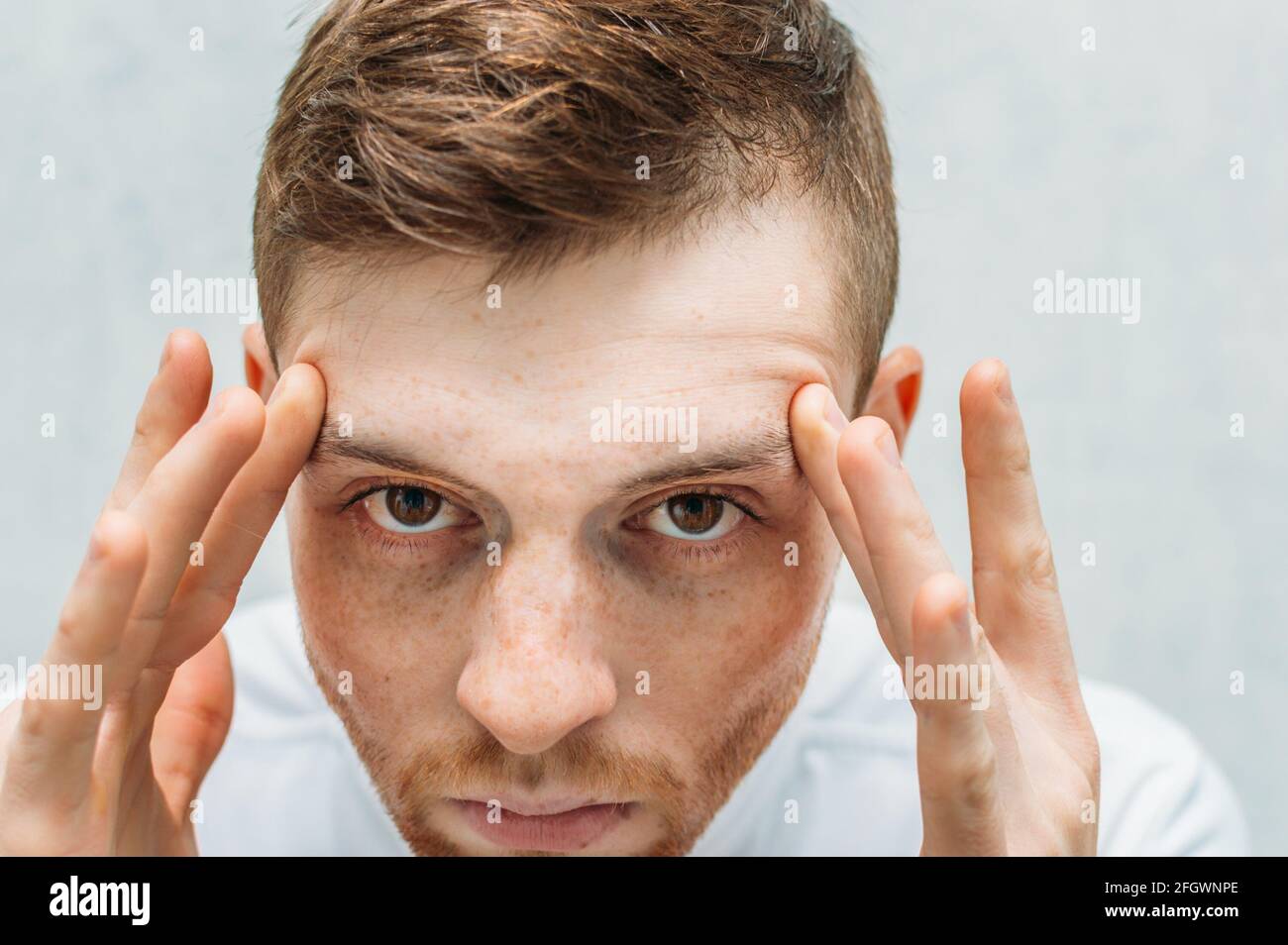 man holds his head with his hands. Headache, migraine attack, high blood pressure. Low blood pressure. Stock Photo
