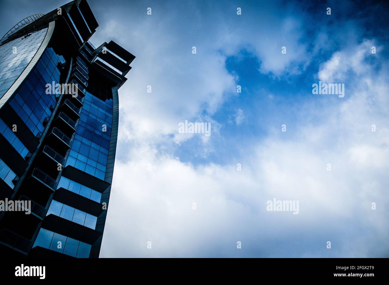 A low angle shot of a tall skyscraper with blue windows and balconies ...