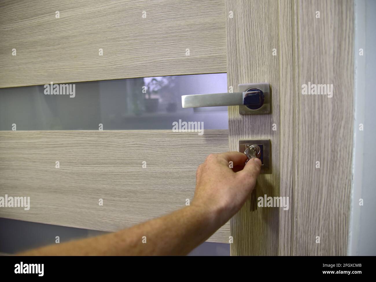 Hand opening door with key. Home door with lock and key closed in room