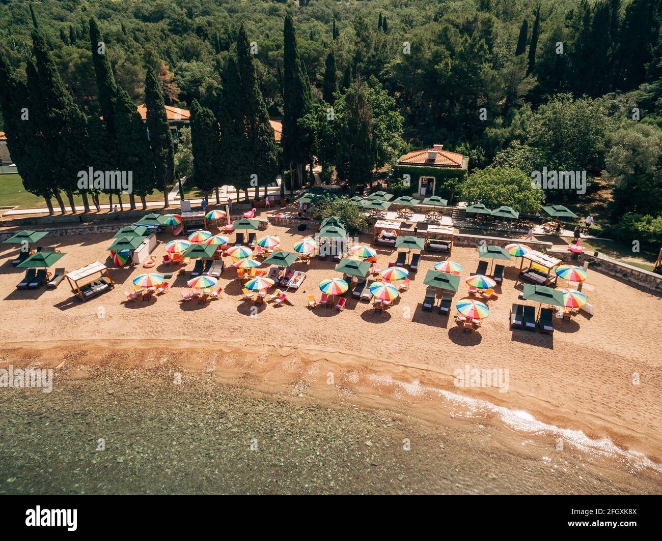 Aerial view of bright sun umbrellas on the royal beach in Przno against the backdrop of green trees Stock Photo
