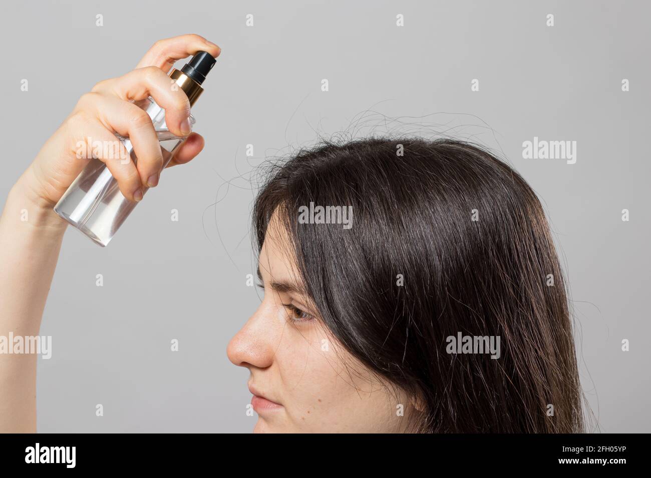 The girl puts on her hair a tonic of hydrolyte from a bottle. Hair care at home. Stock Photo