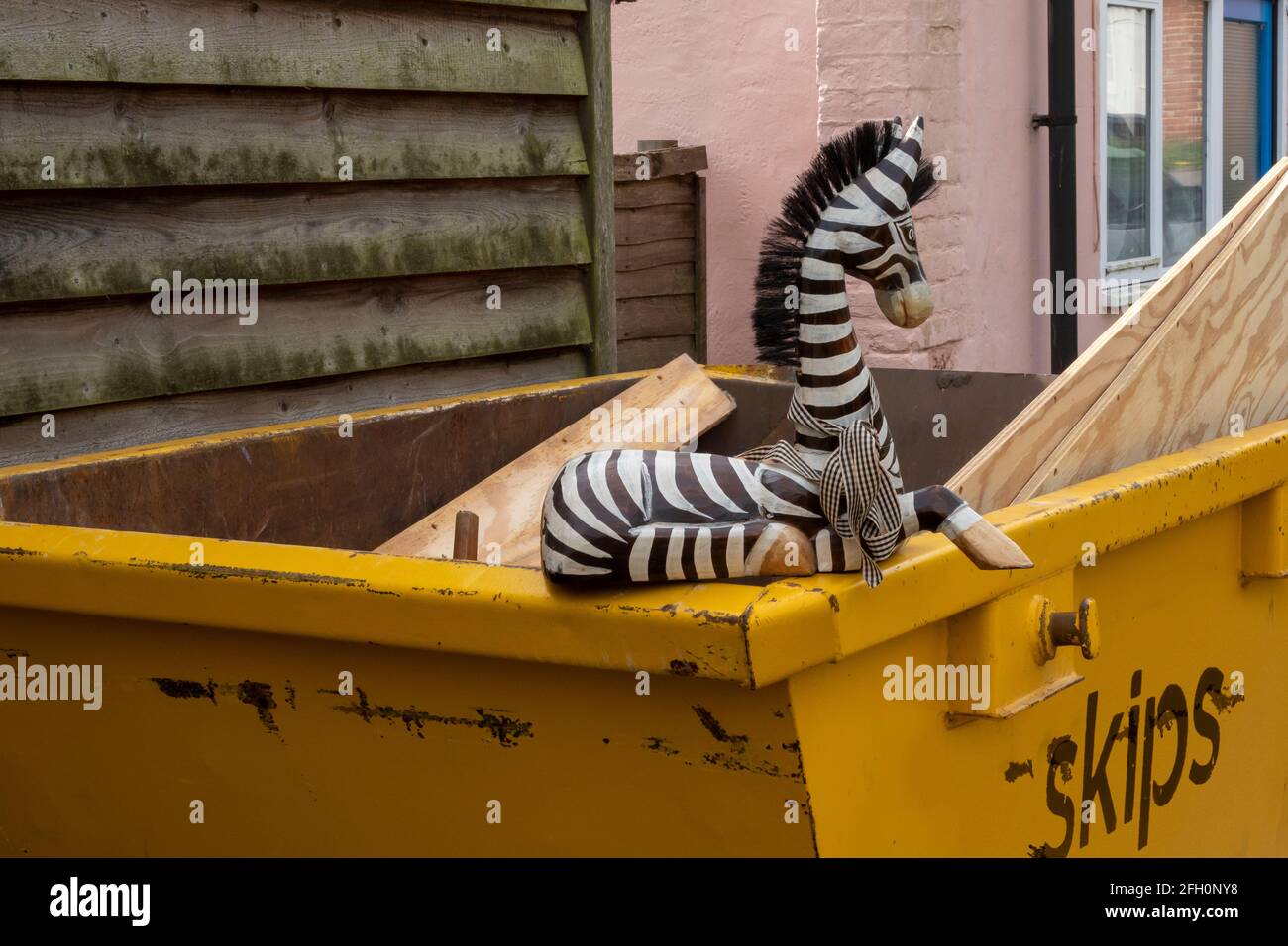 A wooden painted ornamental zebra placed on the corner of a builders' skip Stock Photo