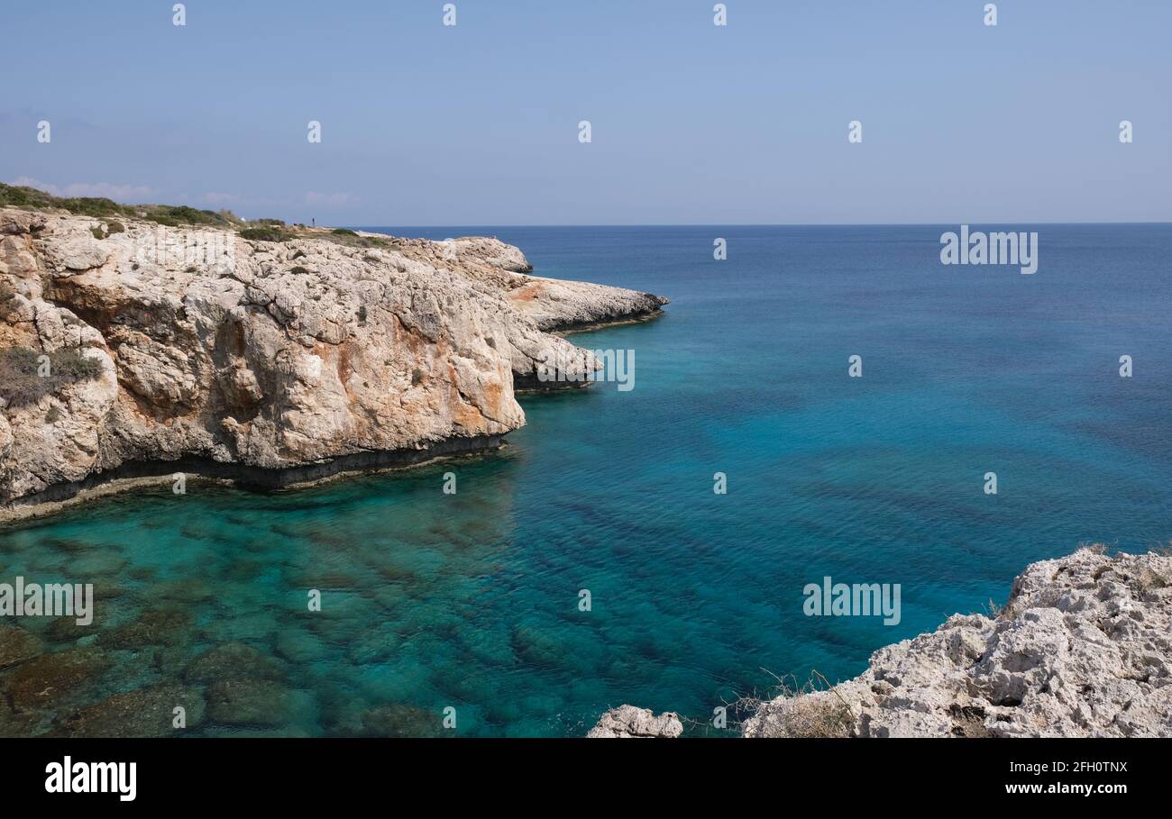 Rocky coastline with blue water and sky. Stock Photo