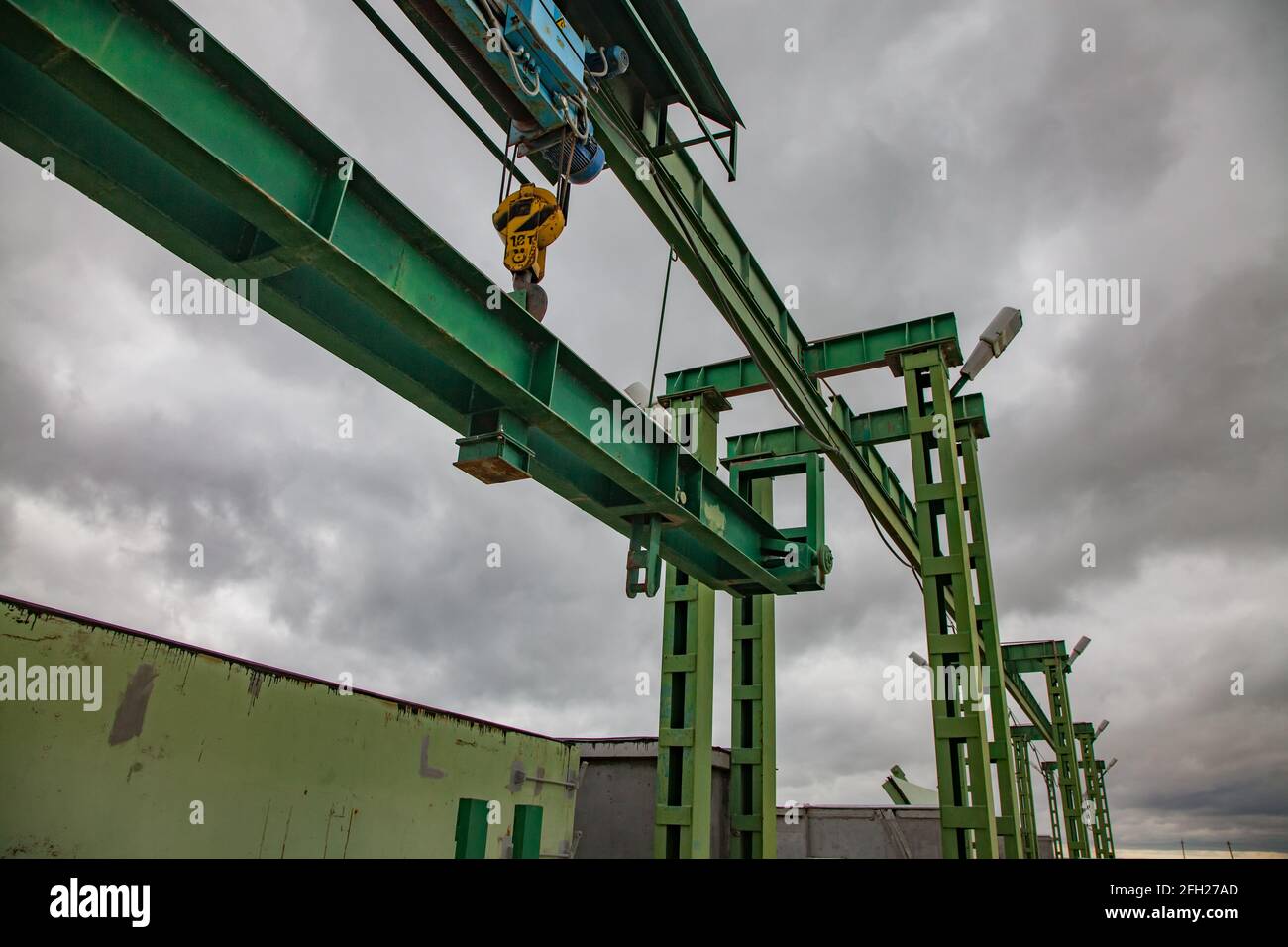 Aklak dam on Shardara river. Lifting machine of water shutter metal  weights. Yellow crane hook. Grey storm clouds. Kazakhstan, Kzylorda region. Stock Photo