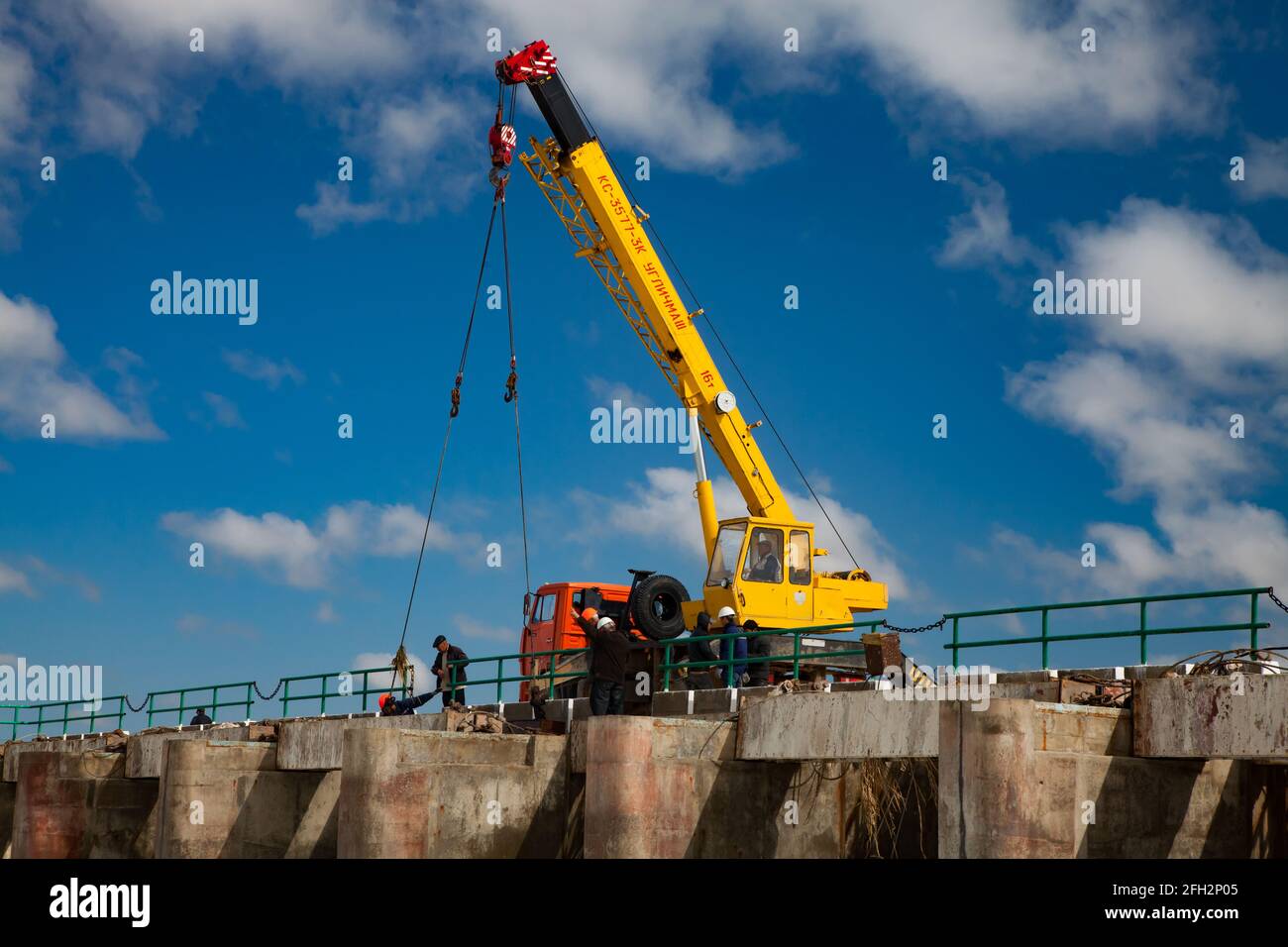 Kok-aral,Kazakhstan:Small Aral Sea Kok-aral dam.Mobile crane and workers lifting water shutters in flood Blue sky, white clouds. Stock Photo