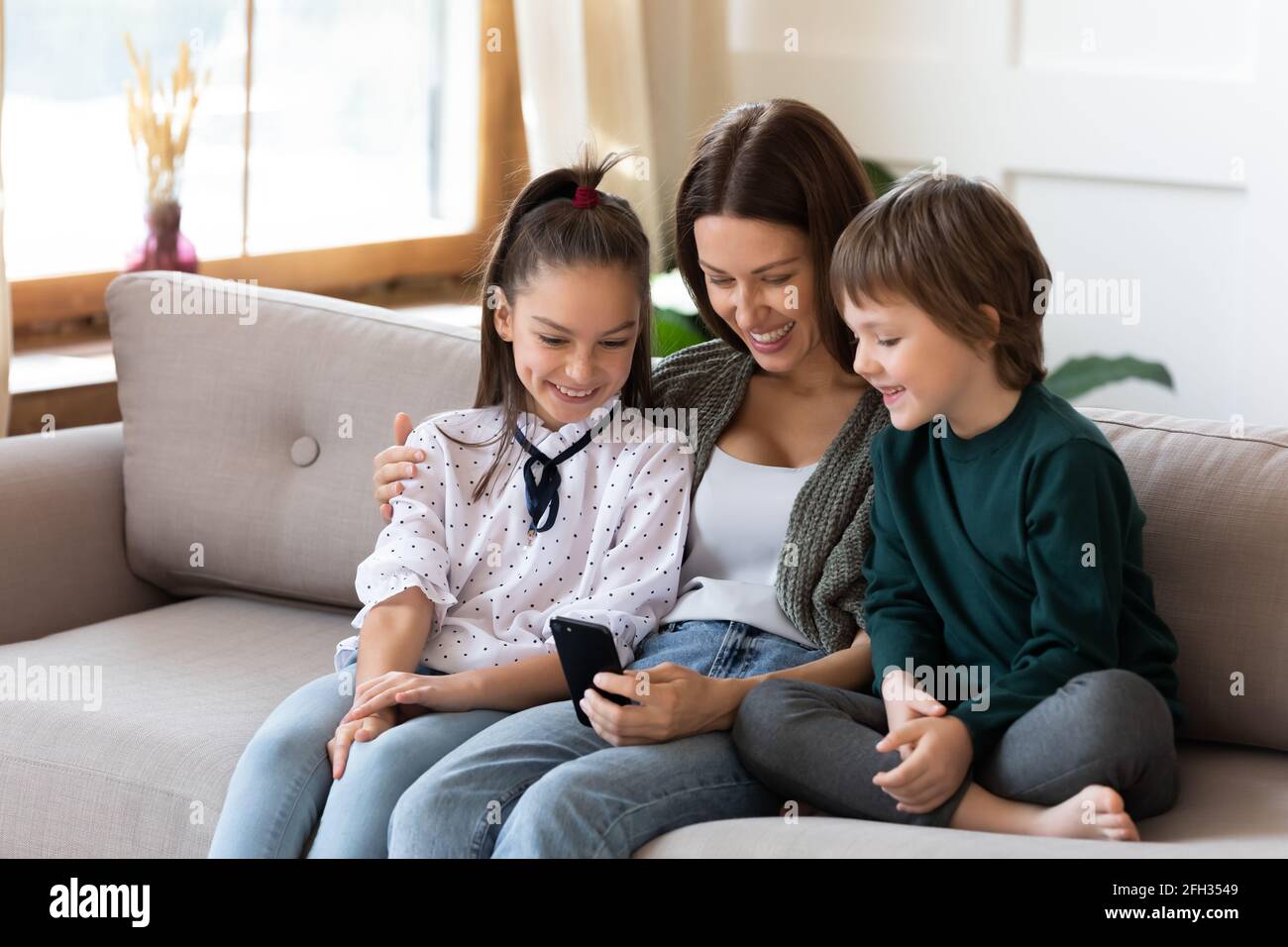 Happy mom use cellphone with two kids Stock Photo - Alamy