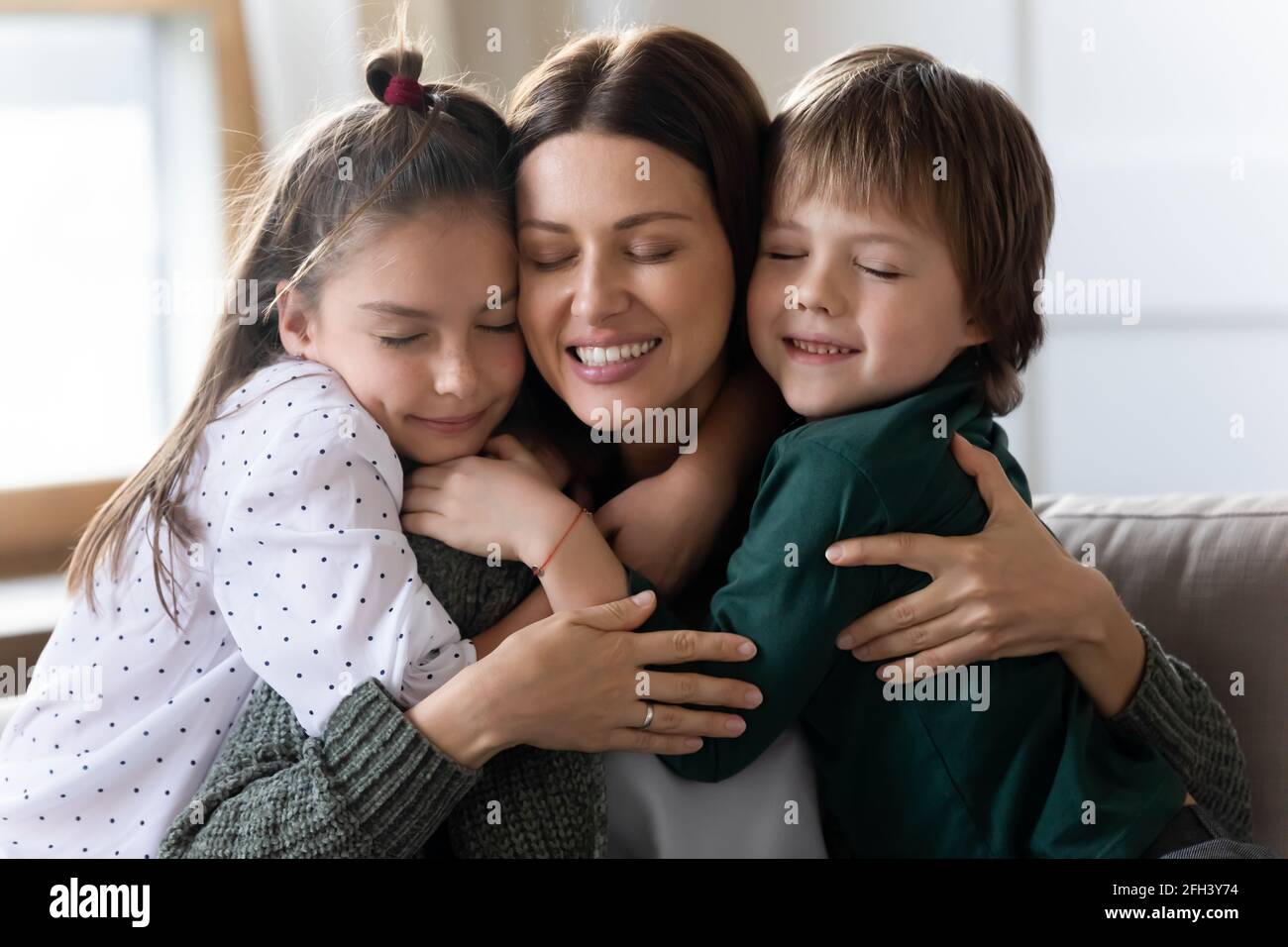 Two little children hug young Caucasian mother Stock Photo