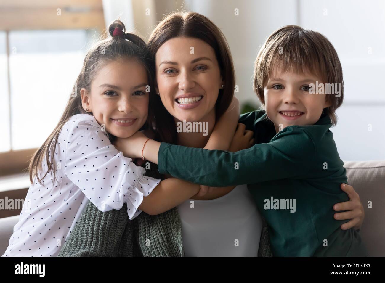 Portrait of happy mom and two small children hug Stock Photo