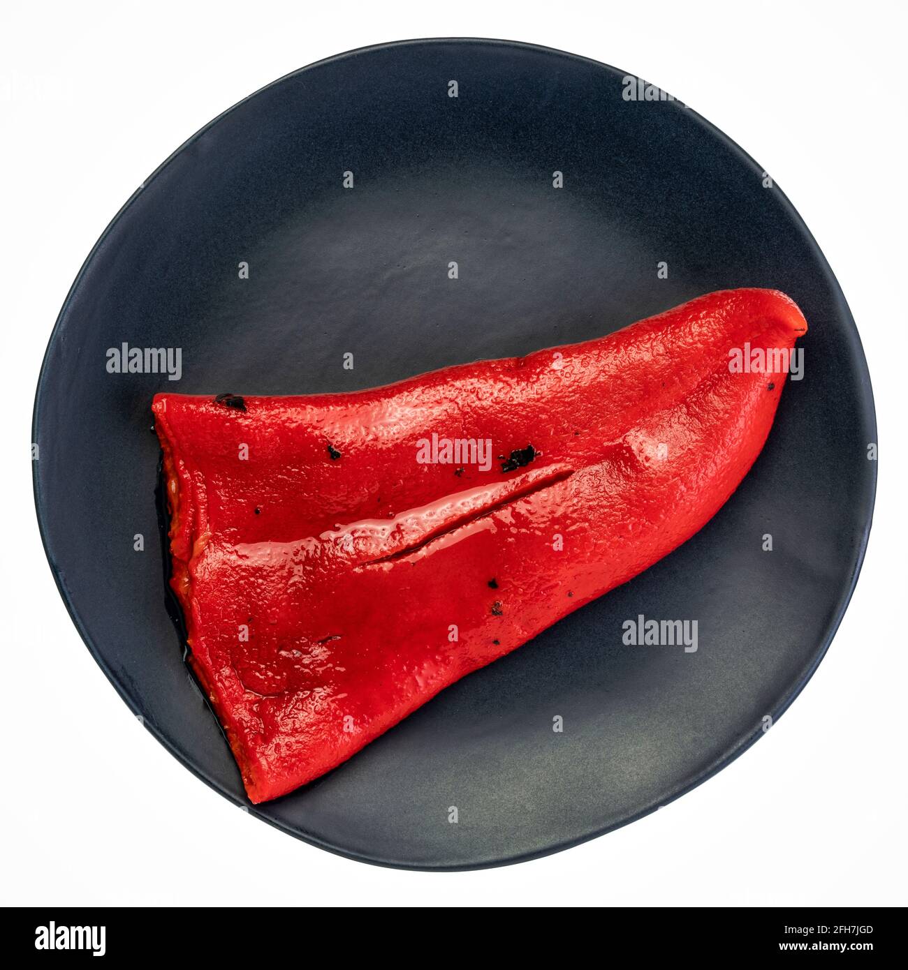 red roasted pepper on an isolated black ceramic plate Stock Photo