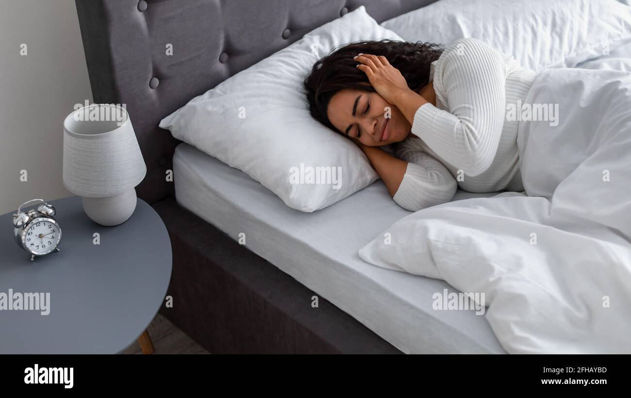 Stressed black woman covering ears lying in bed Stock Photo Alamy
