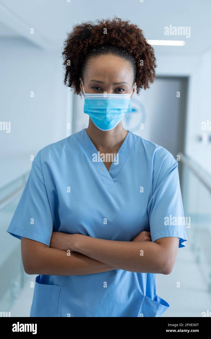 Portrait of african american female doctor wearing mask standing in ...