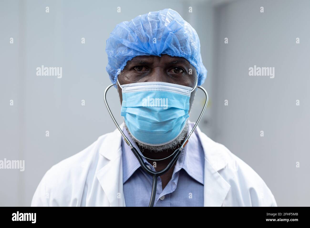 Portrait of african american male doctor wearing face mask surgical cap ...