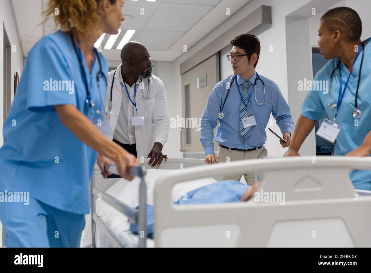 Diverse group of male and female doctors transporting patient on hospital bed Stock Photo