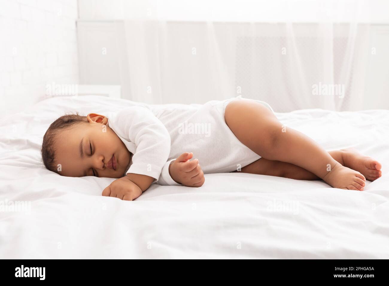 Cute Little Baby Sleeping Lying On Side In Bedroom Indoors Stock Photo