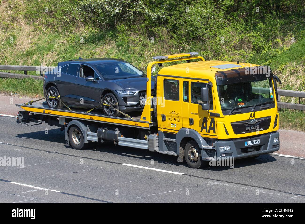 AA Roadside 24hr breakdown roadside recovery;  car carrier transporter Man delivery trucks, carrying broken down car transportation, roadside rescue truck, cargo, vehicle, delivery, commercial transport industry, on the M61 at Manchester, UK Stock Photo