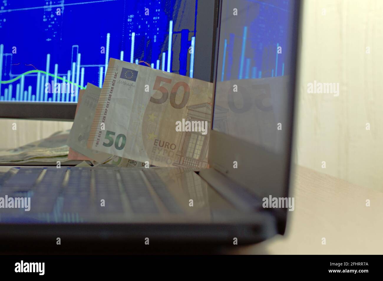 50 euro banknote close up on blurred background of computer screen and monitor with stock chart. Focus in center of image Stock Photo