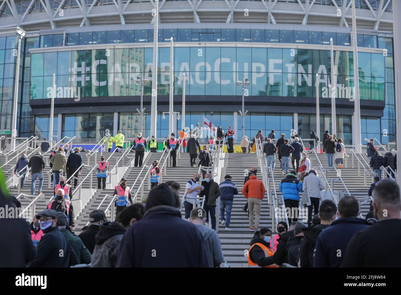 Wembley Stadium, Wembley Park, UK. 25th April 2021.Spectators on the Olympic Steps outside Wembley Stadium ahead of the Carabao Cup Final match between Manchester City and Tottenham Hoptspur.  8,000 local residents, NHS Staff and fans are expected to attend the match, the largest number of spectators attending a sporting event in a UK stadium for over a year.  Covid-19 Lateral Flow testing will take before and after the match and data gathered will be used to plan how all events can take place following lockdown. Amanda Rose/Alamy Live News Stock Photo