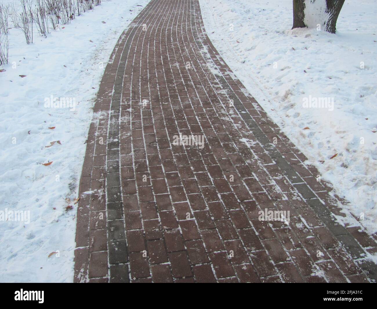 A tiled path in a snow-covered park Stock Photo