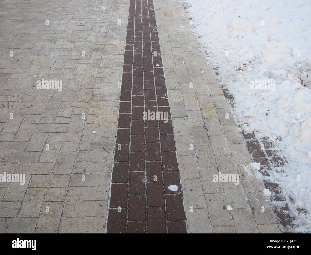 A tiled path in a snow-covered park Stock Photo