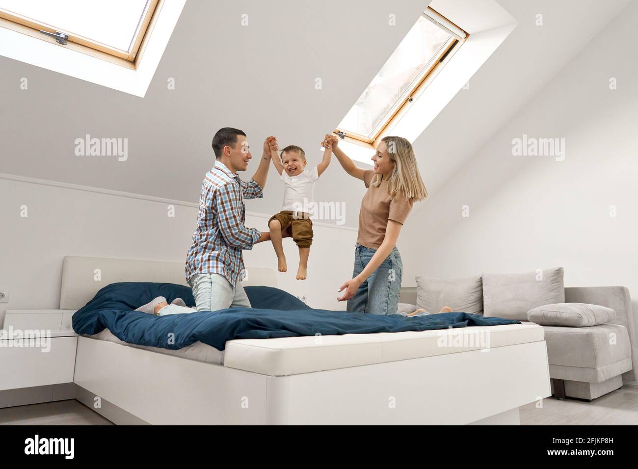 Happy family playing with small toddler kid son together in bedroom at home. Stock Photo