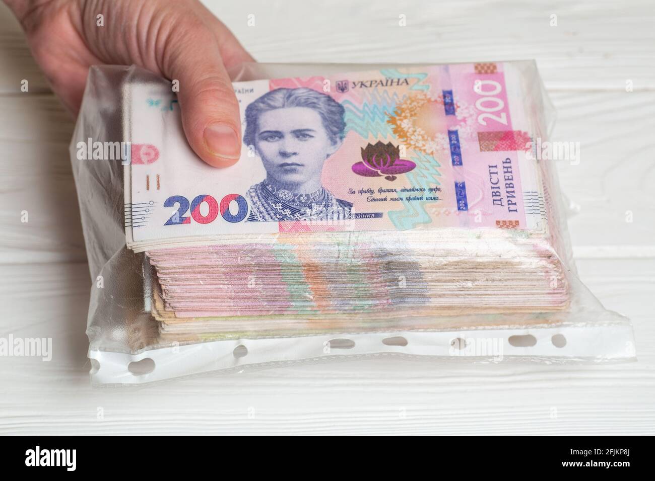 Money of Ukraine. Stack of ukrainian hryvnia banknotes in plastic transparent bag in hands Stock Photo