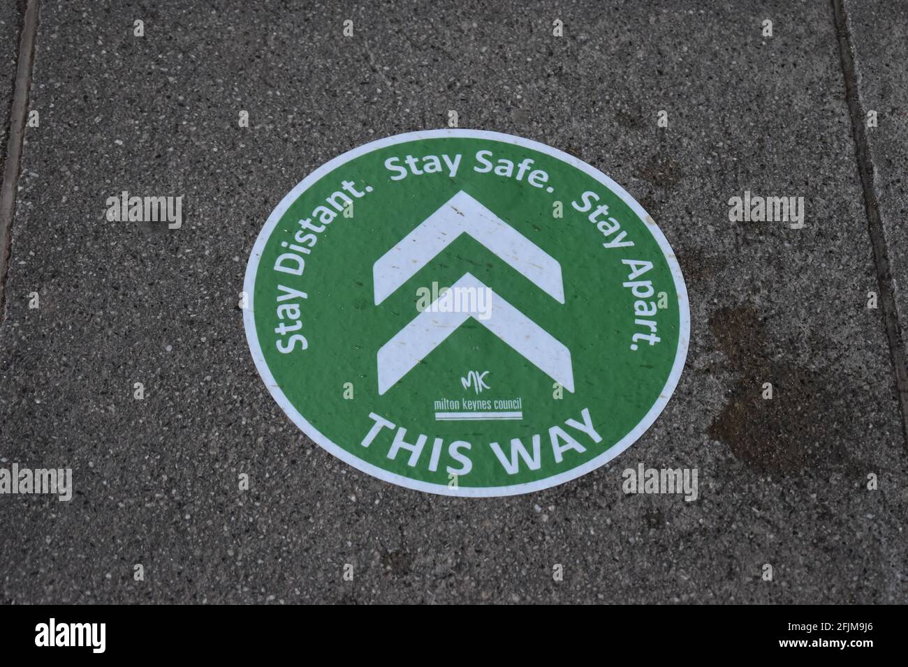 Social distancing sticker on a pavement in Central Milton Keynes. Stock Photo