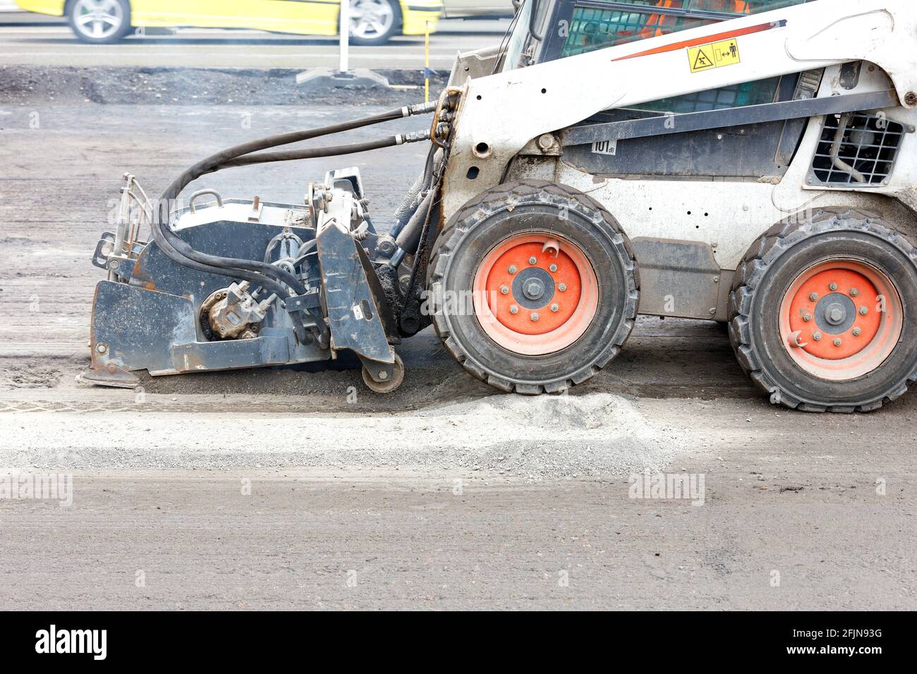 Compact road tractor with hydraulic road repair attachment destroys old asphalt before paving new one. Copy space. Stock Photo