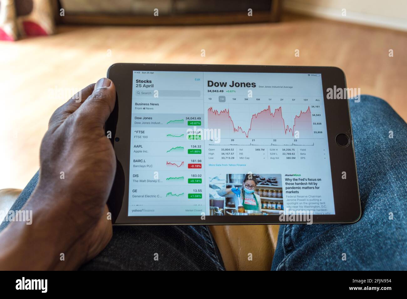 Adult male age 35 seated on sofa and checking Stock market prices on ipad Stock Photo