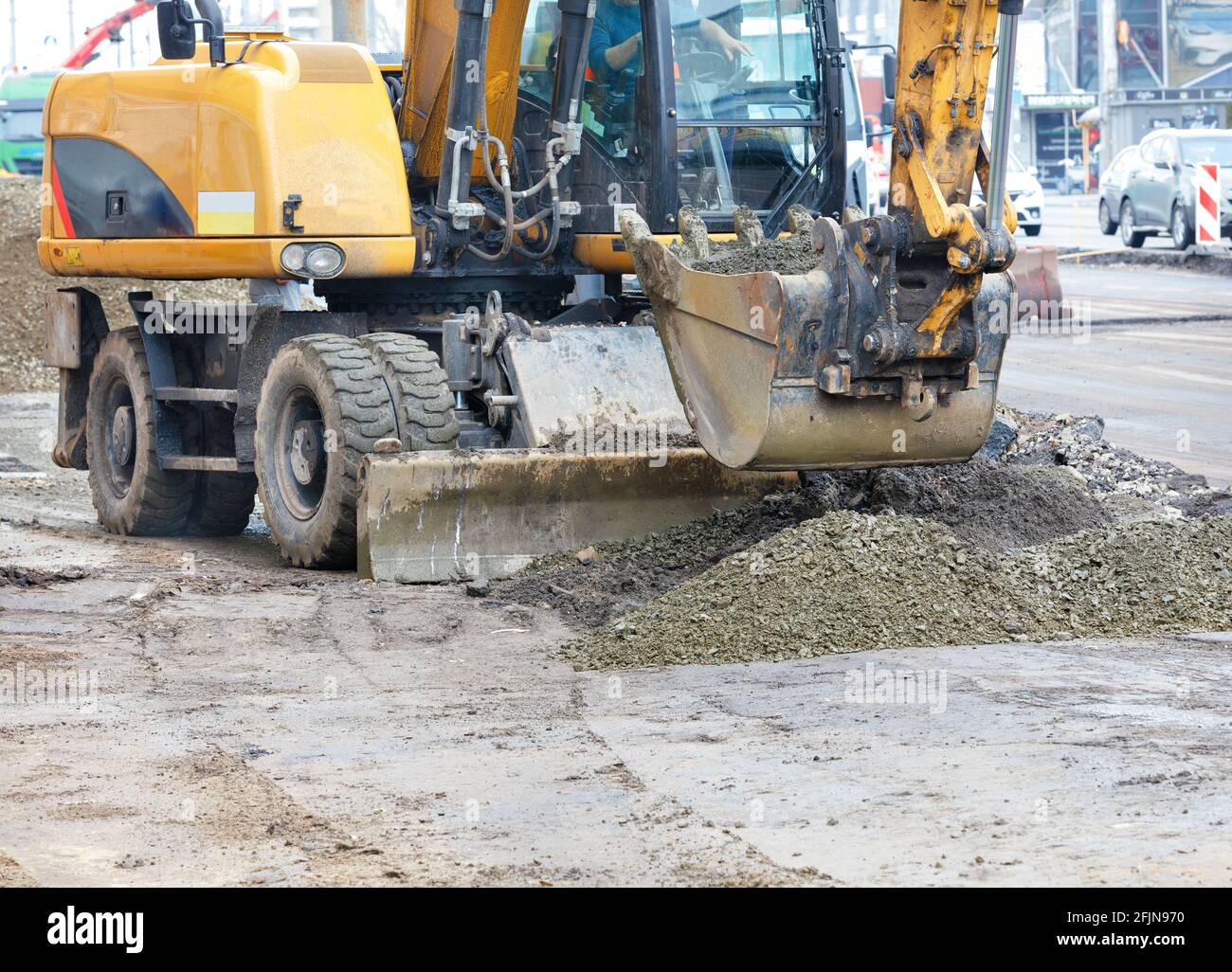 A road excavator bucket evenly distributes rubble to create a ...