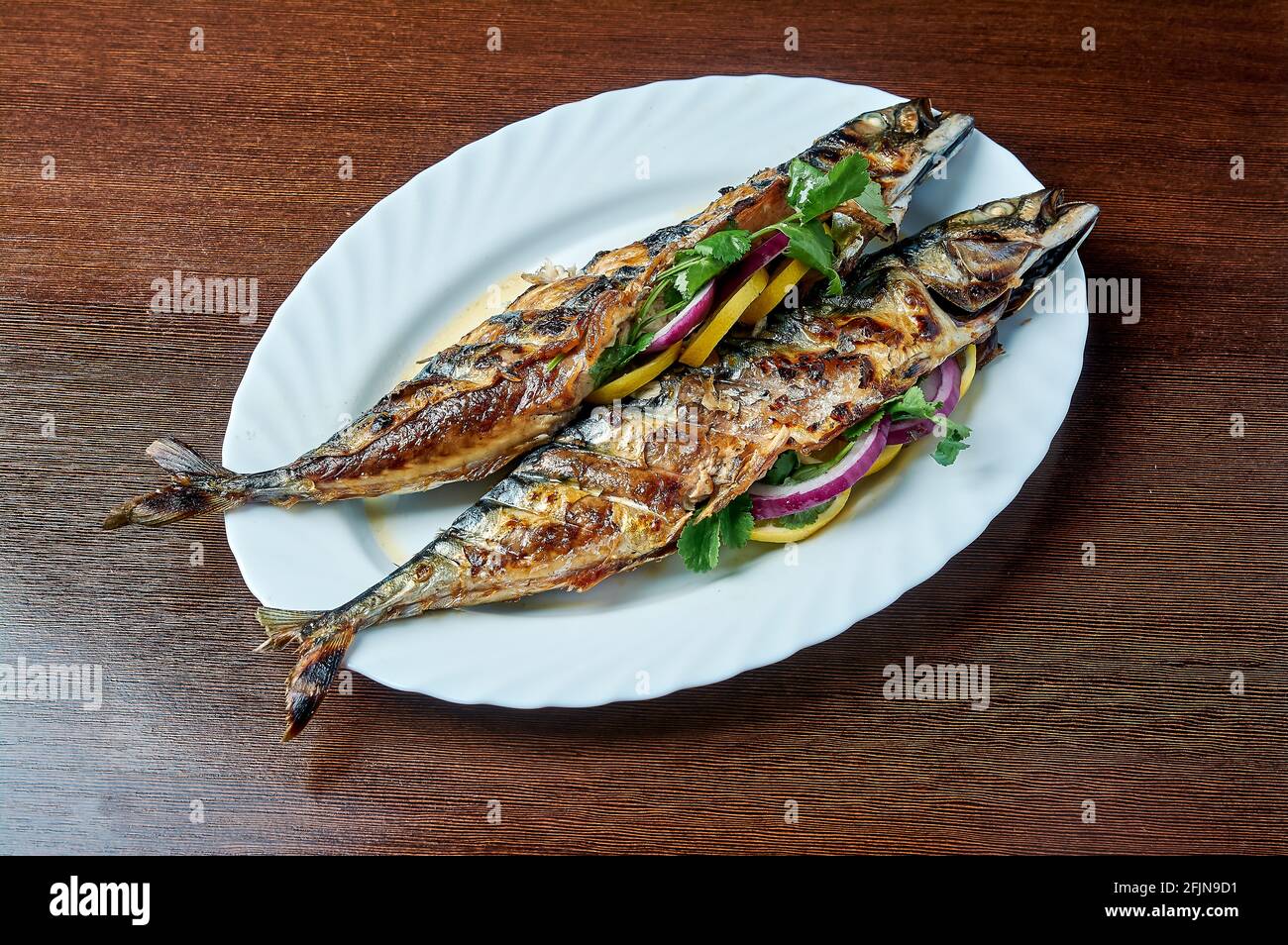 Mackerel baked on the grill lies on a white plate Stock Photo