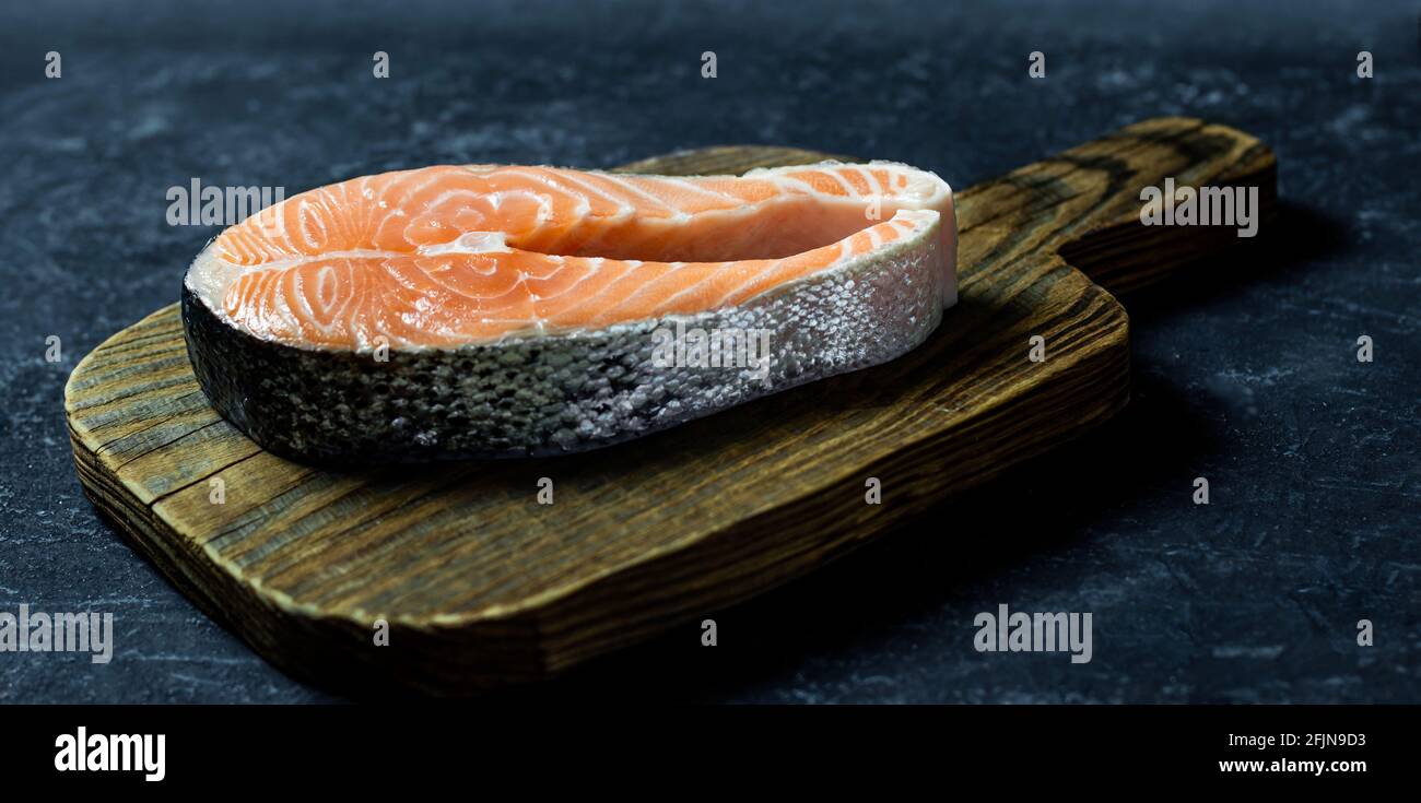 Fresh raw salmon fish steak on dark stone background Stock Photo - Alamy