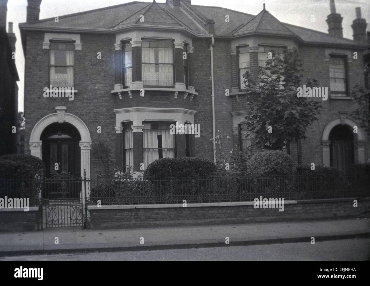 1940s, historical, exterior view of two semi-detached Victorin houses at Seven Kings, Ilford, Essex, England, UK. These large two-storey properties were built around 1850 and had ornate, decorative stone work around the windows and entrance that set them apart from other victorian semi's. Stock Photo