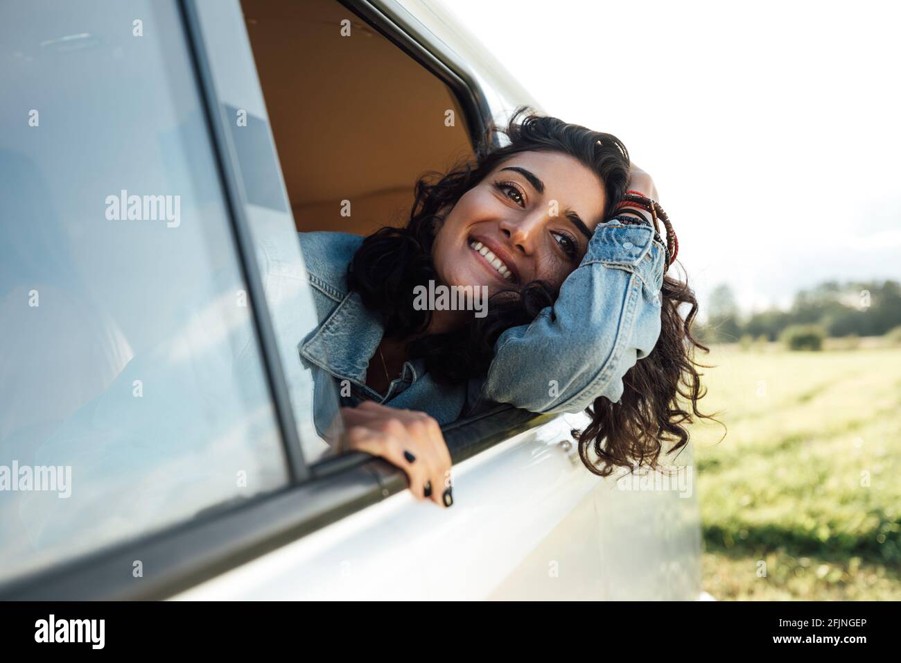 Attractive young woman enjoying road trip. Smiling female looks out Stock Photo