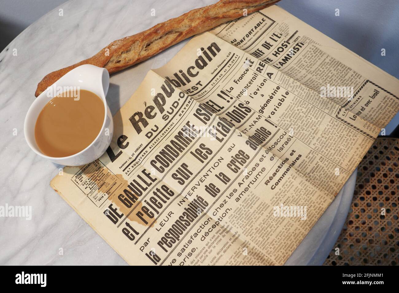 die Zeitung Le Republicain du Sud-Ouest mit der Schlagzeile 'deGaulle verturteilt Israel' liegt am 22.Juni 1967 auf einem Cafe-Tisch in Biarritz, daneben eine Tasse Cafe-au-lait und ein Baguette 'Parisienne', Kaffe-Fleck auf der Zeitung * French newspaper 'Le Rublicain' of June 22,1967 on a coffeetable mit a cup of cafe-au-lait and  baguette with top headline 'deGaulle condemns Israel' Stock Photo